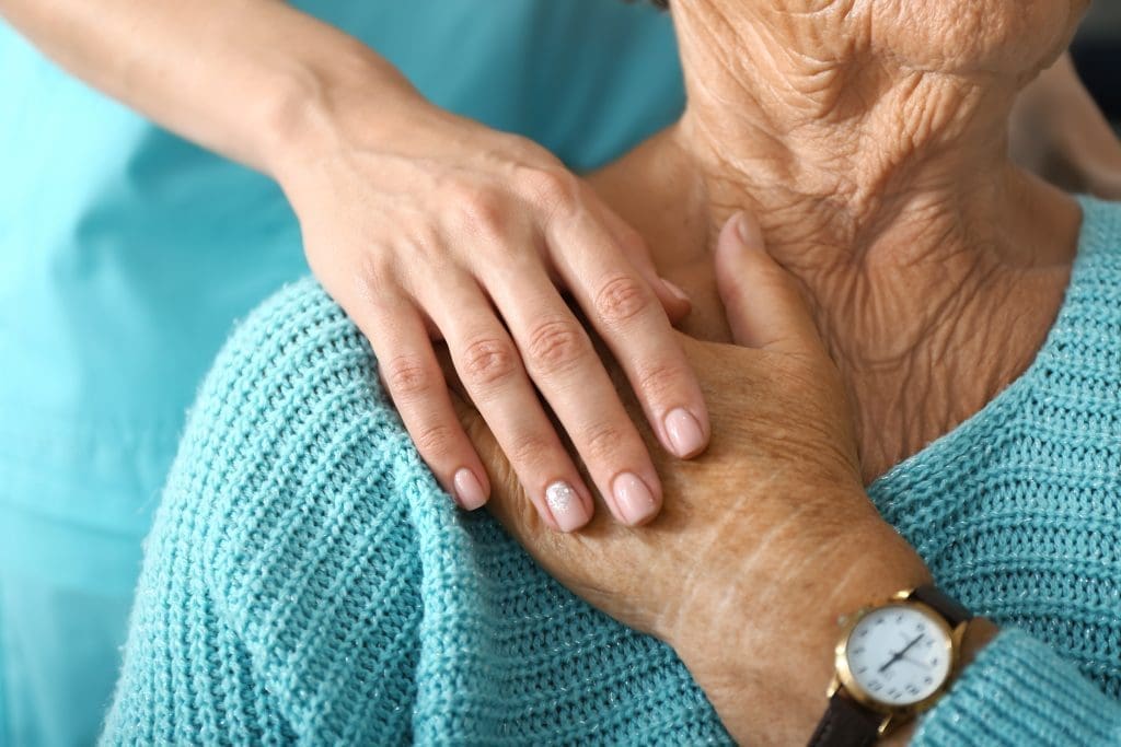 Aide a domicile posant sa main sur l'épaule d'une dame âgée